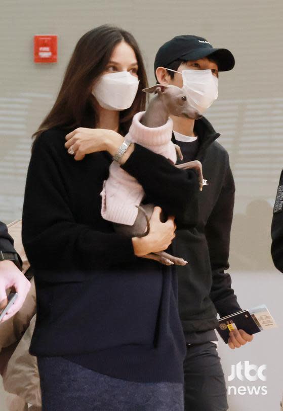妻子凱蒂抱著愛犬，身穿黑衣黑裙也掩飾不住孕肚。 圖：翻攝自JTBC News