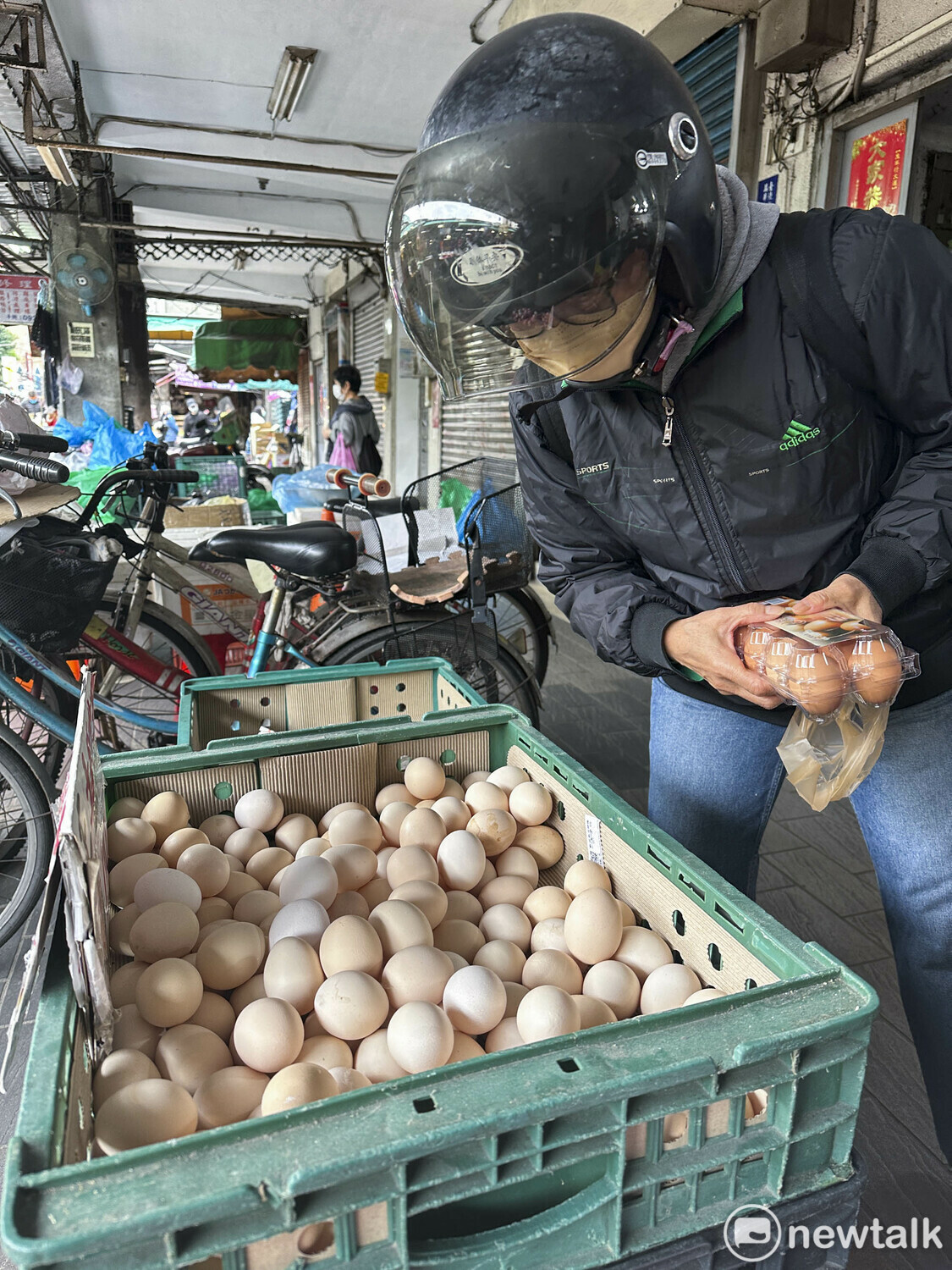 一位民眾看著一斤要價110元的土雞蛋時，猶豫著要不要出手購買。 圖：張良一/攝