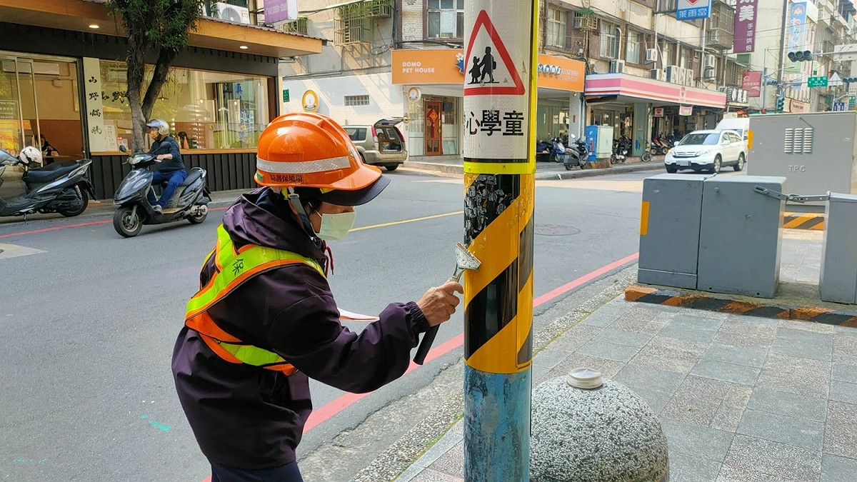 清潔隊撕除小廣告後刮除殘留的黏貼痕跡。 圖：新北市環保局提供