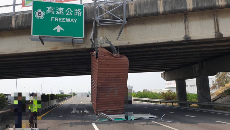 一輛半聯結貨櫃車4日途經國道1號台南麻豆路段時，貨櫃不明原因彈起撞擊上方標誌牌面而卡在跨越橋及中線車道間，幸無人受傷。 圖：國道公路警察局第四警察大隊提供