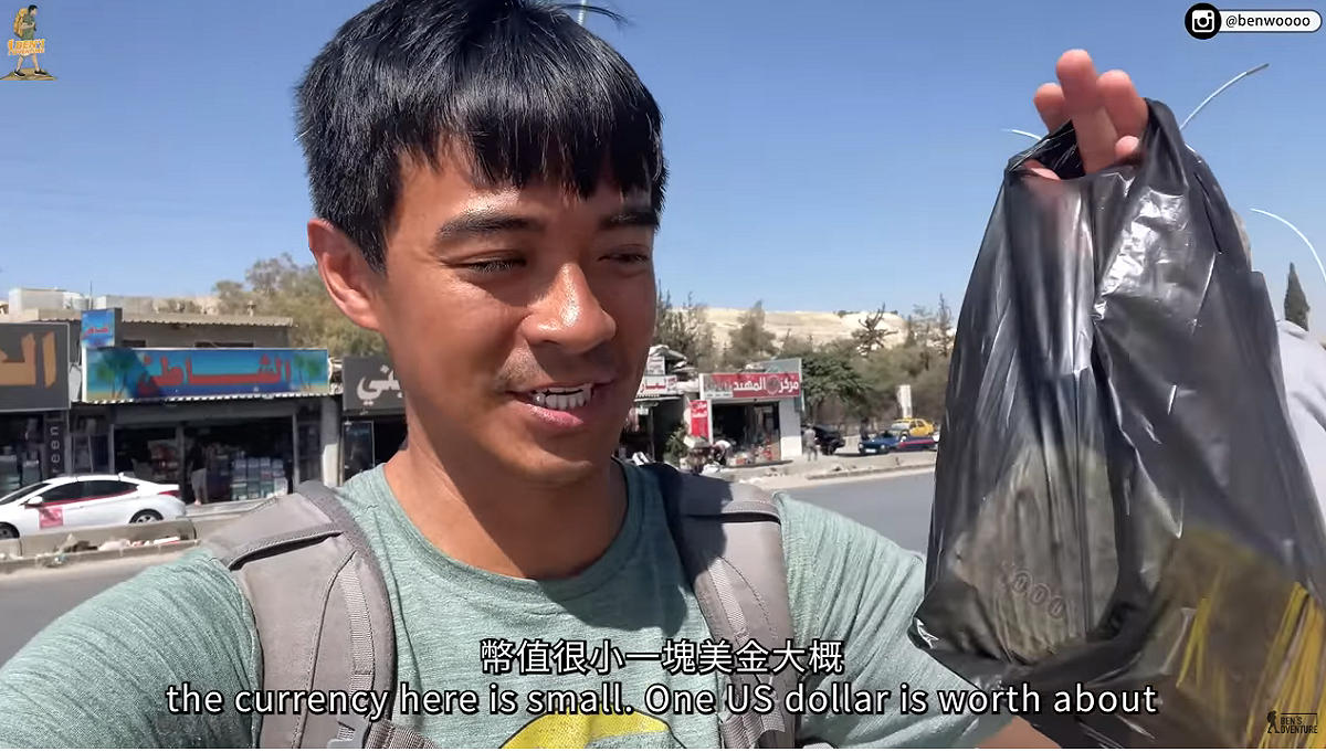 到敘利亞後，融融換完錢就直接拎著一袋錢在大家上走。 圖：翻攝自融融歷險記YT頻道