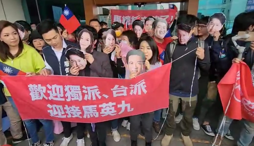 徐巧芯率同黨議員戴著名嘴面具到桃園機場接機馬英九，諷刺台派、獨派名嘴願賭不服輸。 圖：林昀真／翻攝