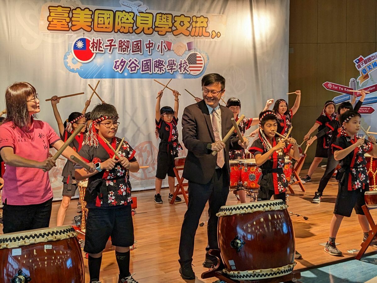 新北市教育局長張明文（右）、桃子腳國中小校長郭昱晨（左）與學生一起進行太鼓表演，歡迎60位國際學伴。 圖：新北市教育局提供