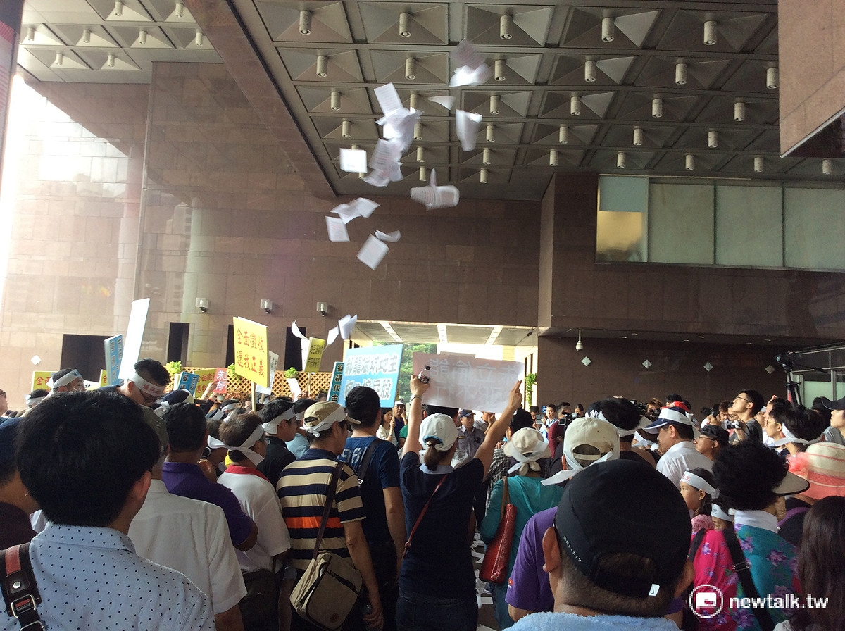 地主與警推擠衝突後，開始在現場拋撒預先複印的「土地權狀」，諷政策讓權狀成為廢紙。 圖：程士華/攝
