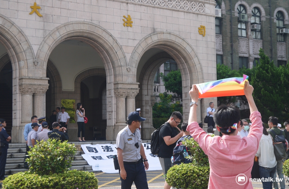 臺灣大學法研所學生獨自一人前往司法院高舉彩虹旗支持同性婚姻法案。 圖：鍾孟軒/攝