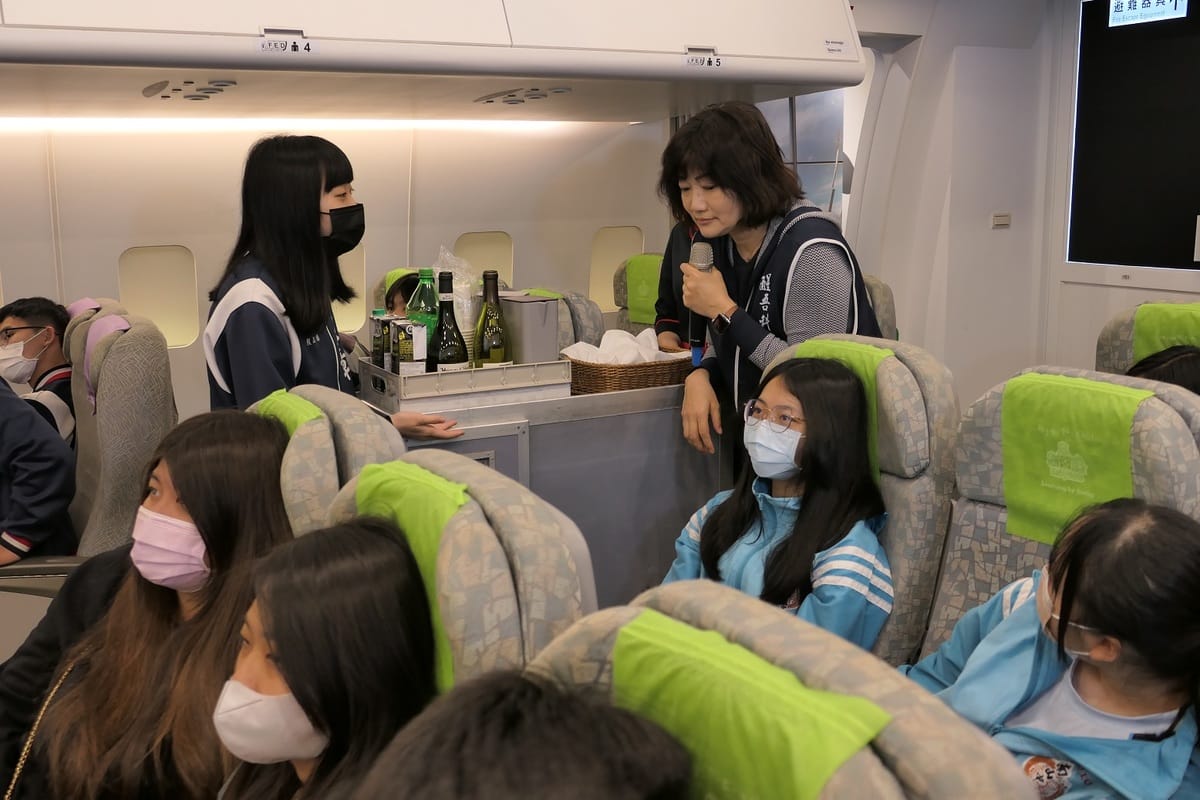 醒吾科大旅運系老師沈曉華（後排右）直接帶學生進行飛機客艙中的餐飲服務，體驗當個空姐了解職場英語。 圖：吾限熊報社潘奕成/攝