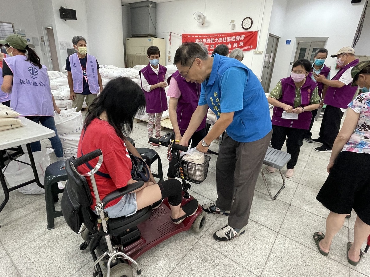 板橋區長陳奇正協助行動不便者搬運米糧。 圖：板橋區公所提供