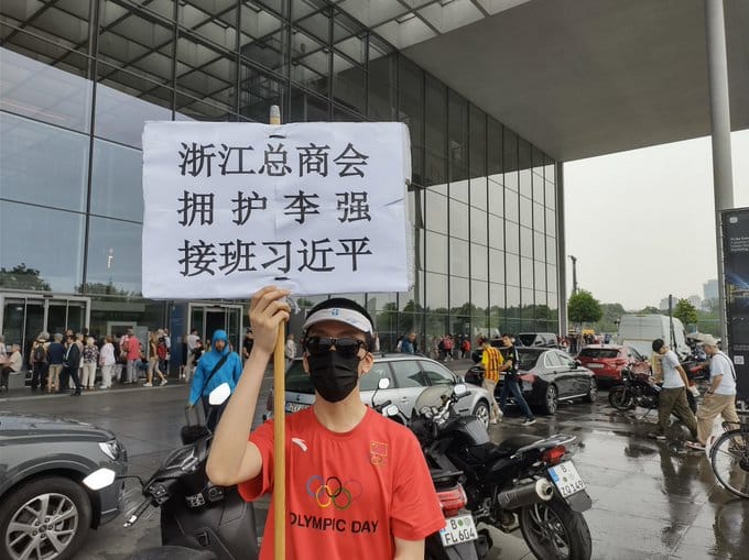 李強於 19 日出訪德國期間，有一名疑似浙江人在德總理府外，舉牌呼籲要擁護李強接班習近平。 圖：翻攝自推特用戶「 Jacobson貼貼BOT」