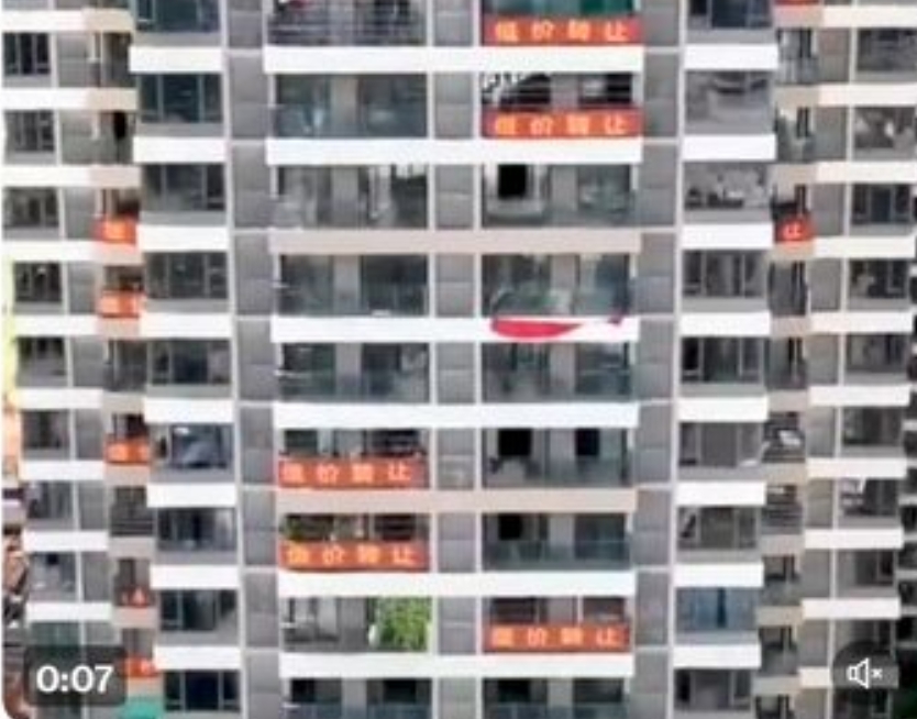 中國房市價格崩跌，一棟大樓就有多戶住宅同時掛出銷售布條。 圖 : 翻攝自微博