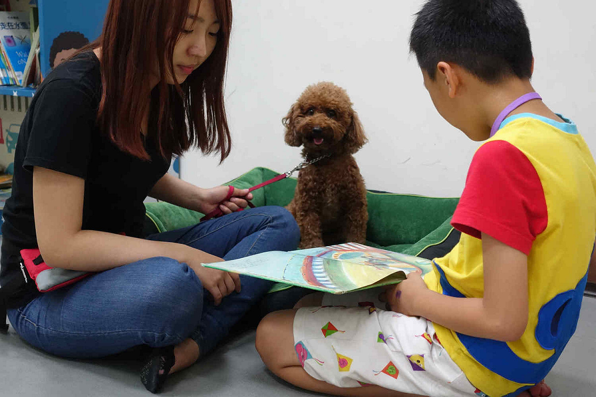 領犬員正引導孩子專注閱讀。 圖：教育部學生事務及特殊教育司提供