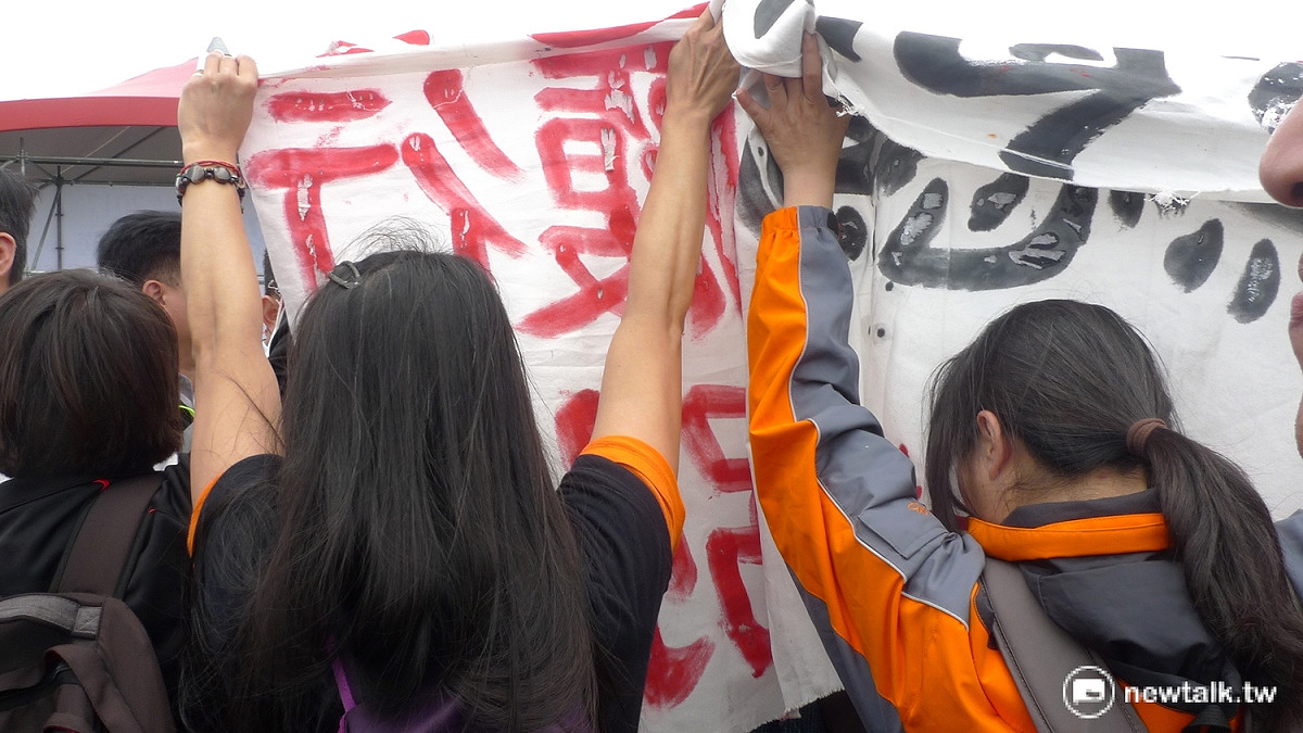 國道收費員在重重維安人員包圍拉扯下，仍拼命舉起布條。 圖：汪少凡／攝