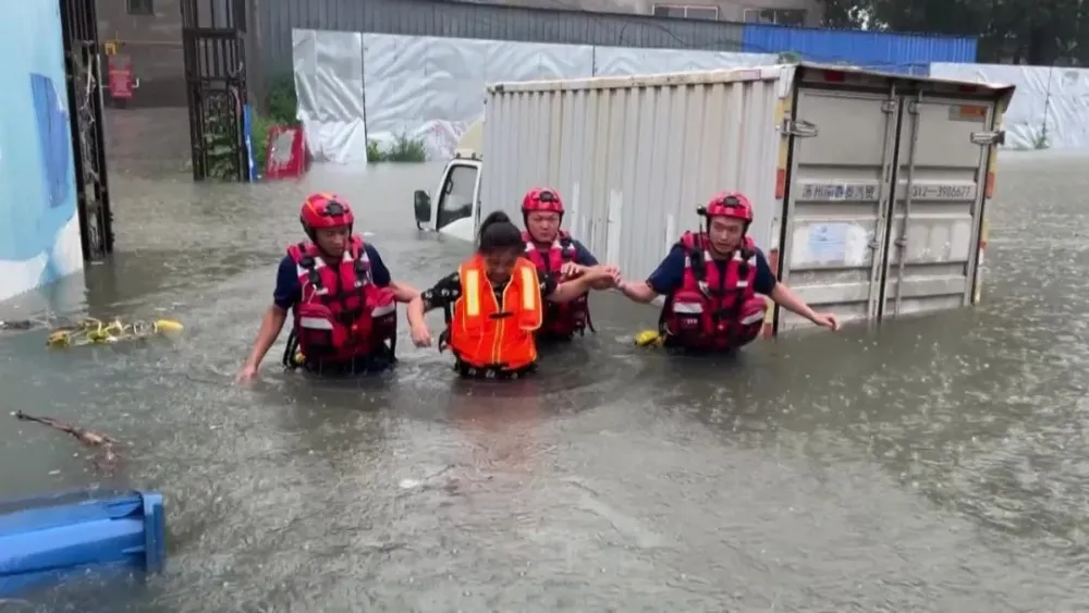 北京暴雨，河北省涿州面臨嚴重洪災，搜救隊員救出一名受困卡車的婦女。 圖：翻攝自騰訊網／《南方人物周刊》