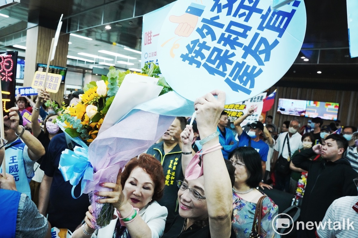 支持者拿著鮮花和歡迎侯友宜的手舉牌，簇擁著侯友宜到他的座車停車點。 圖：張良一/攝