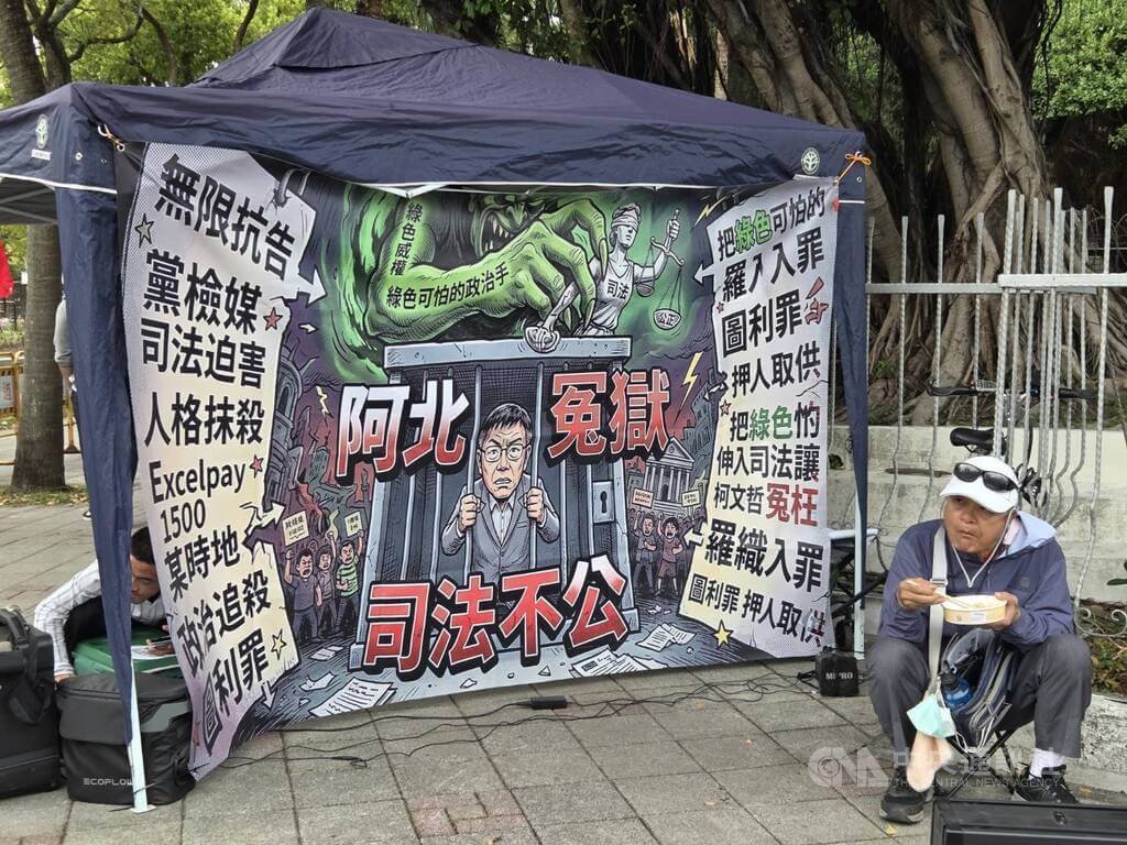 台北地院審理京華城、柯文哲政治獻金案26日下午2時30分一審宣判。前台北市長柯文哲支持者「小草」在北院周邊愛國東路與博愛路口集結，並搭設客廳帳掛上巨幅海報，上面印有綠色惡魔關押柯文哲圖案，寫著「阿北冤獄，司法不公」等字眼。中央社記者謝君臨攝　115年3月26日