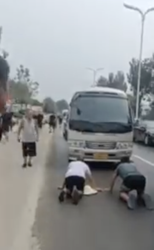 涿州災民跪在官員乘坐的巴士前抗議，希望能當面向官員成情。網友根據車輛分析，推測該車輛為河北省長座車。 圖：翻攝自Ｘ／@fangshimin
