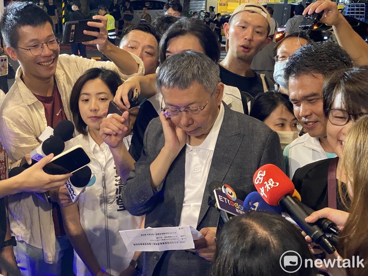 民眾黨總統參選人柯文哲等待鴻海創辦人、無黨籍總統參選人郭台銘進場時，面無表情地看著稿子。 圖：周煊惠 / 攝