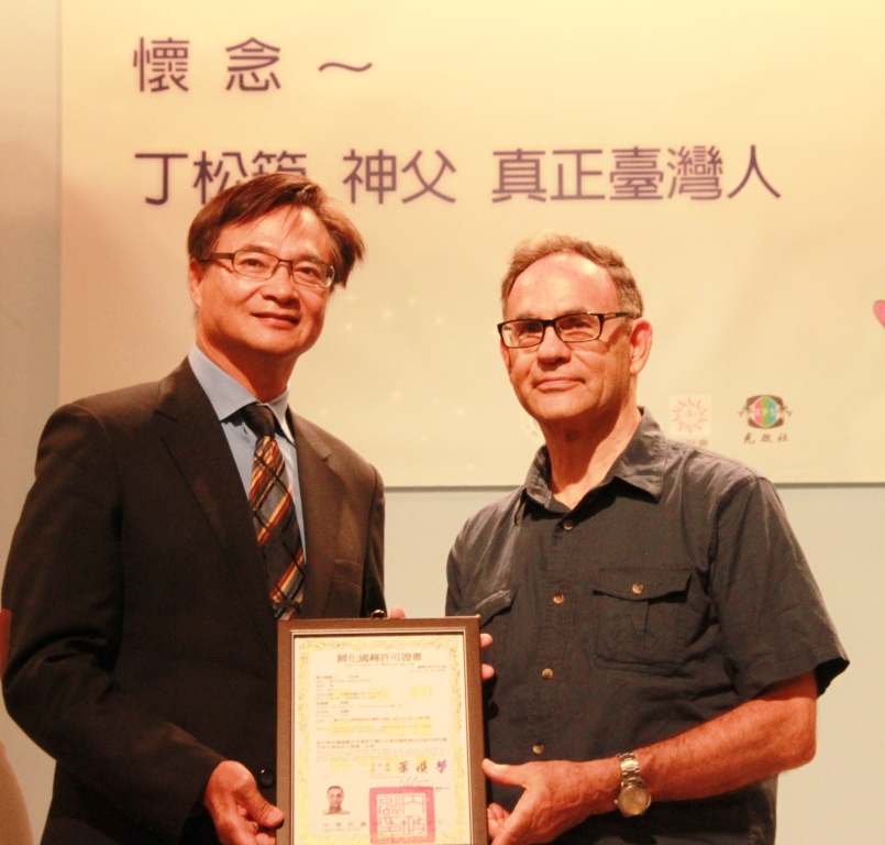 臺北市政府民政局藍世聰局長頒發歸化國籍許可證書，由丁松青神父代領。  圖：台北市政府提供