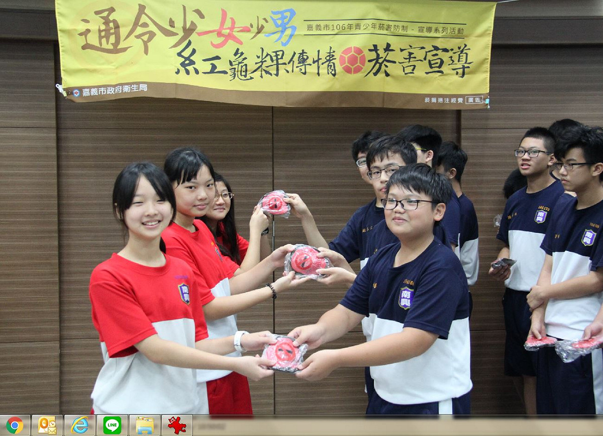 嘉義市衛生局3日舉行「紅龜粿傳情、傳健康」反菸活動，女同學將象徵健康長壽的紅龜粿送給男同學。 圖：嘉義市政府/提供