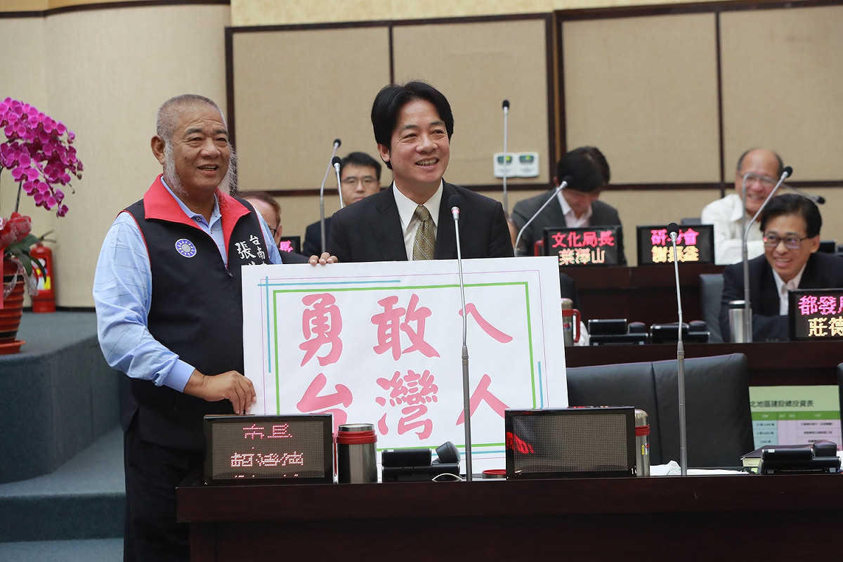 台南市議員張世賢帶著「良心」和「勇敢ㄟ台灣人」看板，質詢賴清德選不選總統、兩岸關係等問題。 圖 :  黃博郎/攝