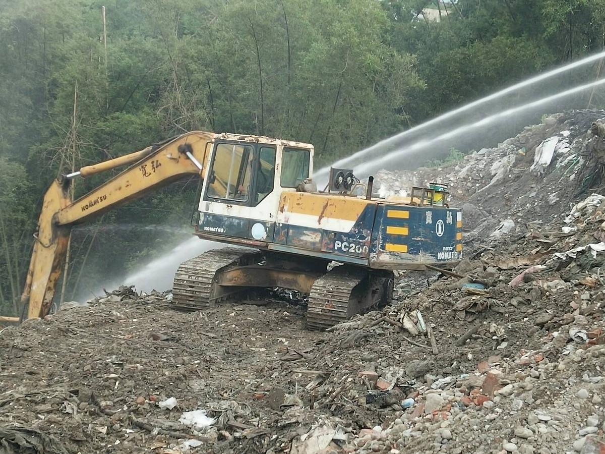 高雄市旗山區旗文路被棄置廢棄物數度悶燒冒煙，高雄市環保局出動灑水車6部，怪手1部，持續以怪手開挖及灑水，目前已暫時滅。 圖:高雄市政府提供