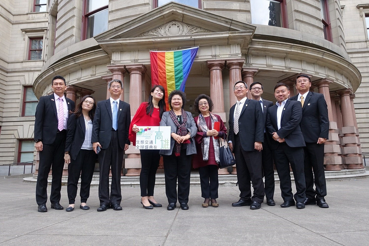 波特蘭市政府前懸掛彩虹旗，與高雄市政府是姊妹市，也一樣信仰「相愛是人權」，所以市府團隊特地於彩虹旗前合影留念。 圖 : 高雄市政府/提供