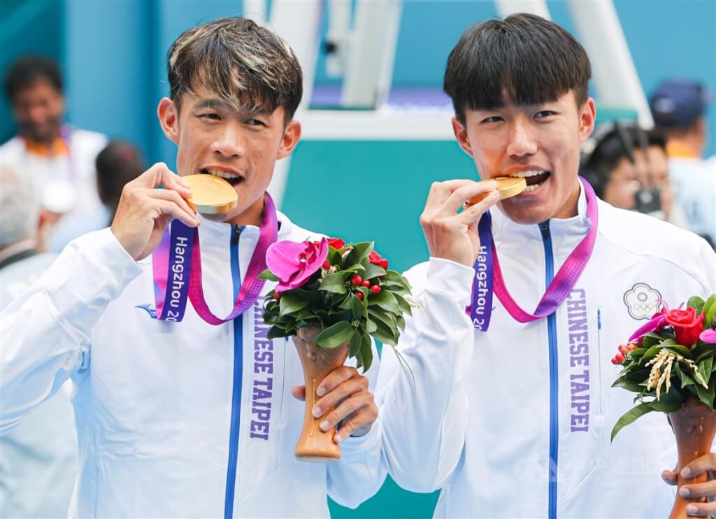 台灣網球選手許育修（右）、莊吉生（左）29日在杭州亞運網球男子雙打項目奪冠，兩人開心咬金牌慶祝勝利。 圖：中央社提供