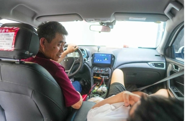 開計程車的易先生，不時會回頭，關懷的看看在副駕駛座的兒子。 圖 : 翻攝自陸媒《北青Qnews》