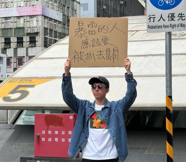 阿滴舉牌「暴雷的人應該要抓去關」。 圖：翻攝自阿滴英文IG