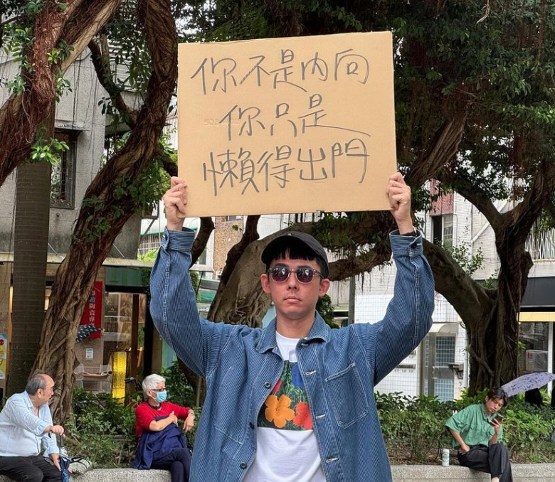 阿滴舉牌「你不是內向，你只是懶惰出門」。 圖：翻攝自阿滴英文IG