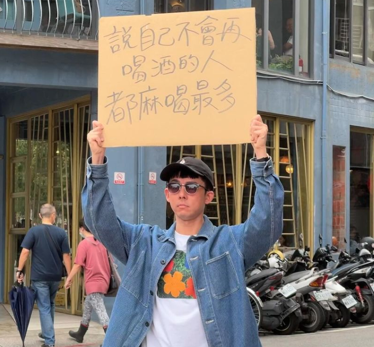 阿滴舉牌「說自己不會再喝酒的人都麻喝最多」。 圖：翻攝自阿滴英文IG