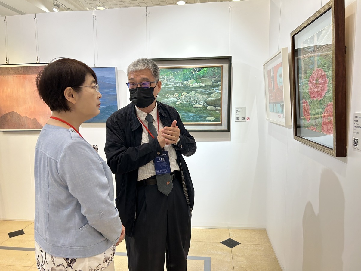 台灣藝術經理人協會前會長李重義為文化局長陳佳君導覽欣賞畫作。 中友百貨/提供