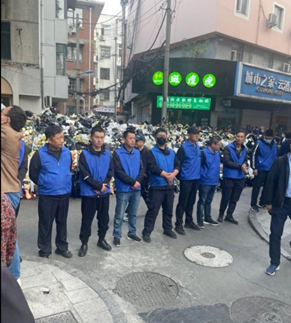 中國網友爆料，李克強頭七過後，身著藍背心的維安人員即迅速清理合肥紅星路 80 號故居周遭，由民眾獻上的大量鮮花。 圖：網上圖片