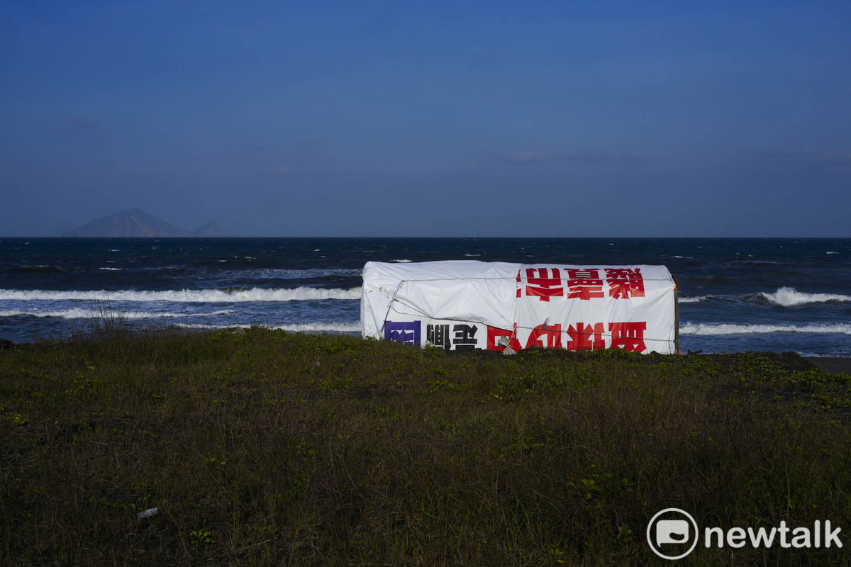 海灘上，競選帆布上攻擊對手的話僅露出支字片語，顯得相當突兀。 圖：張良一/攝