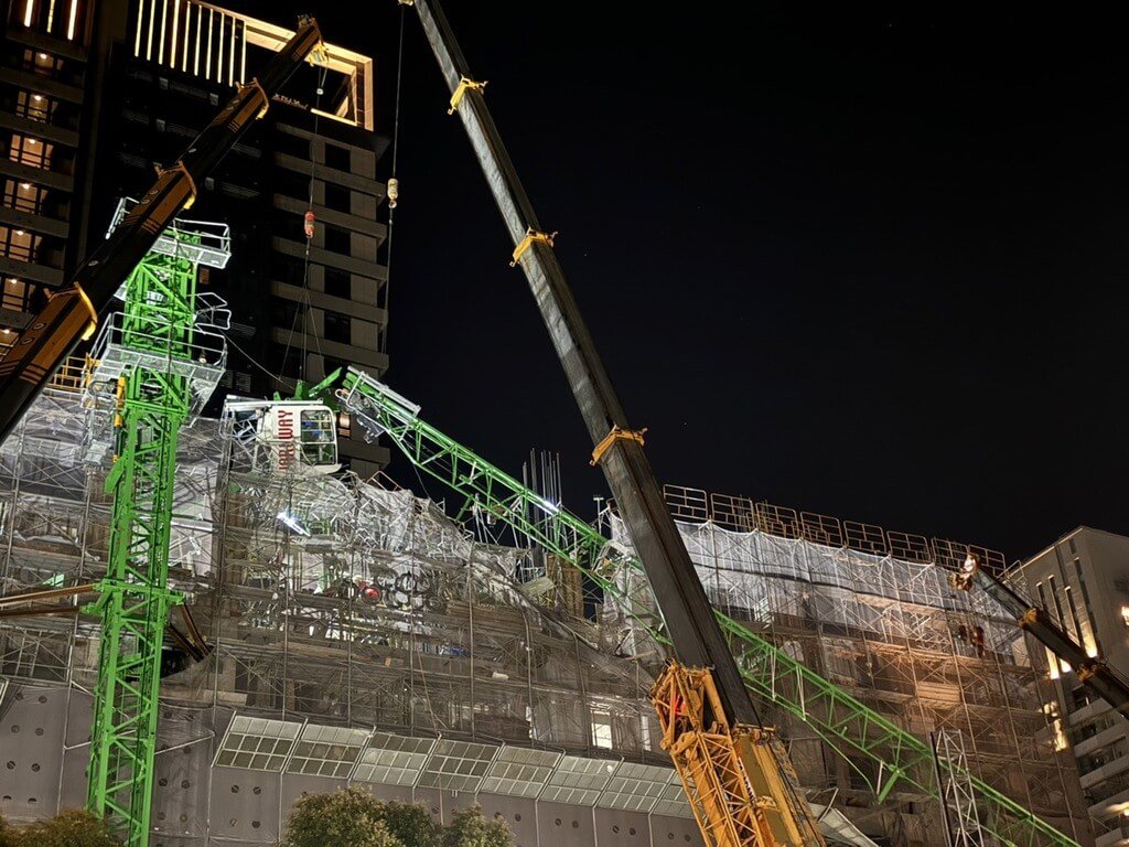 新北市林口區某建案工地28日中午發生塔吊倒塌及吊臂掉落的意外，鐵架險砸中公車站。 圖：工務局提供
