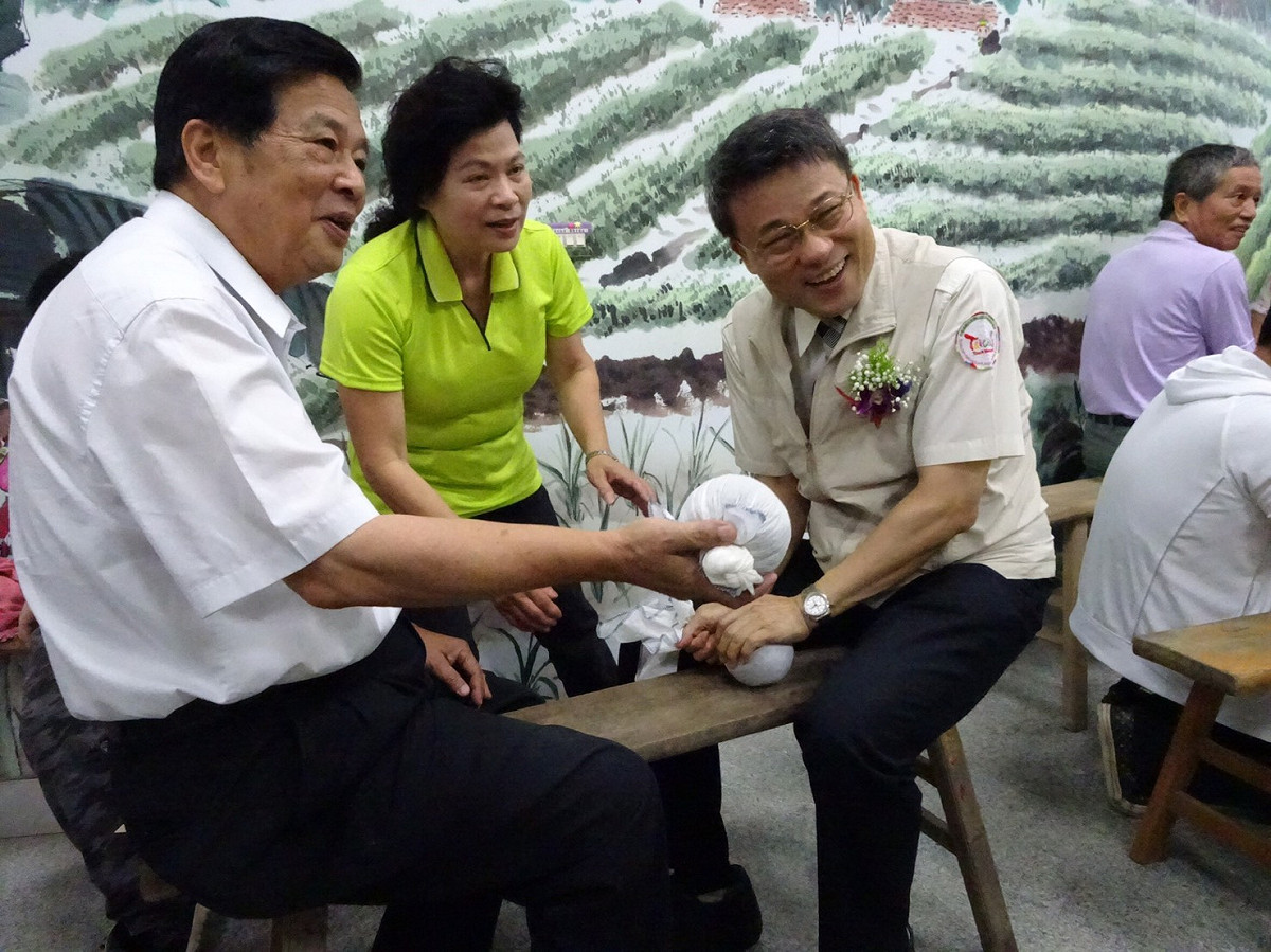 參山處處長吳主治坐在長板凳上體驗早期茶農以長巾揉茶。 圖：參山處/提供