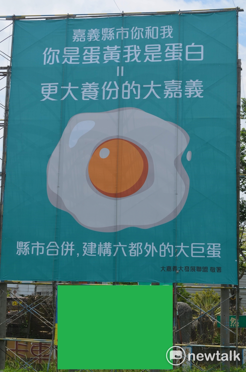 一面「蛋黃蛋白」的戶外看板，引發嘉義縣市政府互別苗頭。 圖：蔡坤龍/攝