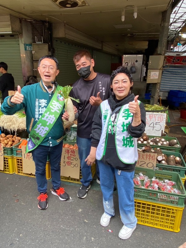 保庇天后王彩樺陪同李坤城到三和市場掃街拜票，攤商老闆送給李坤城菜頭（好彩頭）及蒜頭、蒜苗（凍蒜）。 圖：李坤城競選總部提供