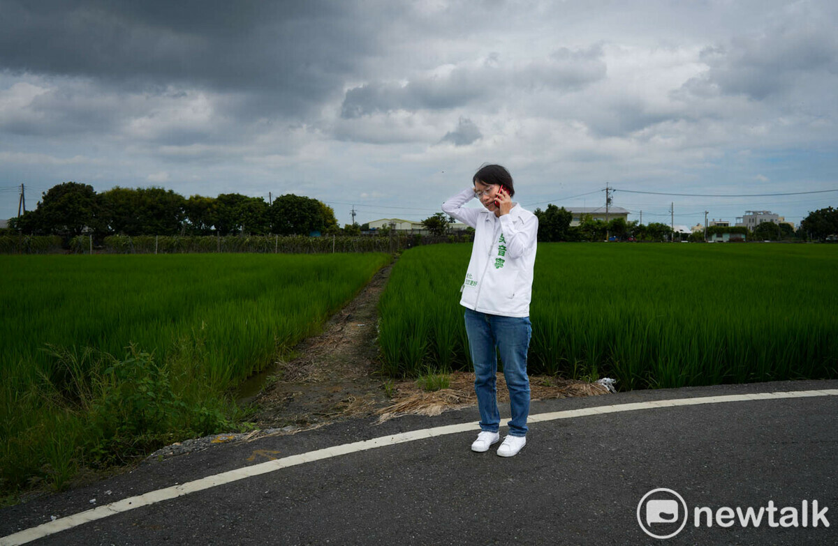 跑行程拜票途中，吳音寧在稻田旁打電話聯絡事情。 圖：張良一/攝