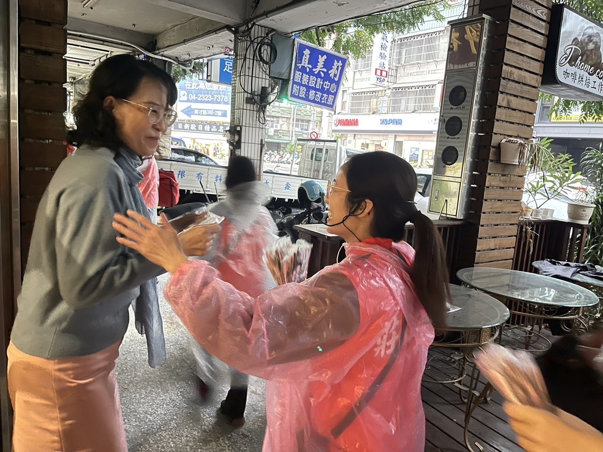 莊競程的太太方心慧穿上輕便雨衣，前往北區淡溝里逐戶請託，受到許多鄉親歡迎，直誇美麗、大方。 莊競程競總/提供