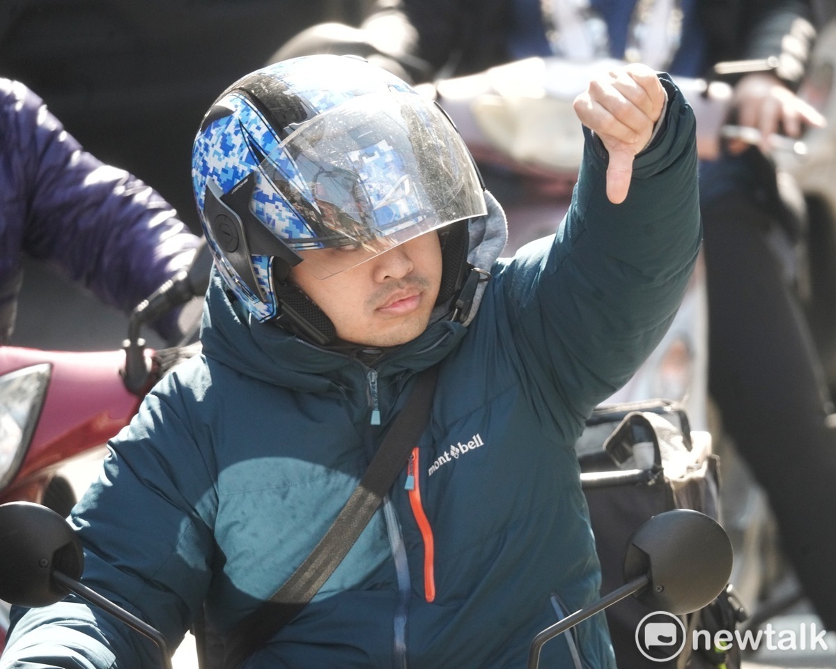 一位機車騎士對著國民黨總統候選人侯友宜比出倒讚手勢，表達對其不認同。 圖：張良一/攝