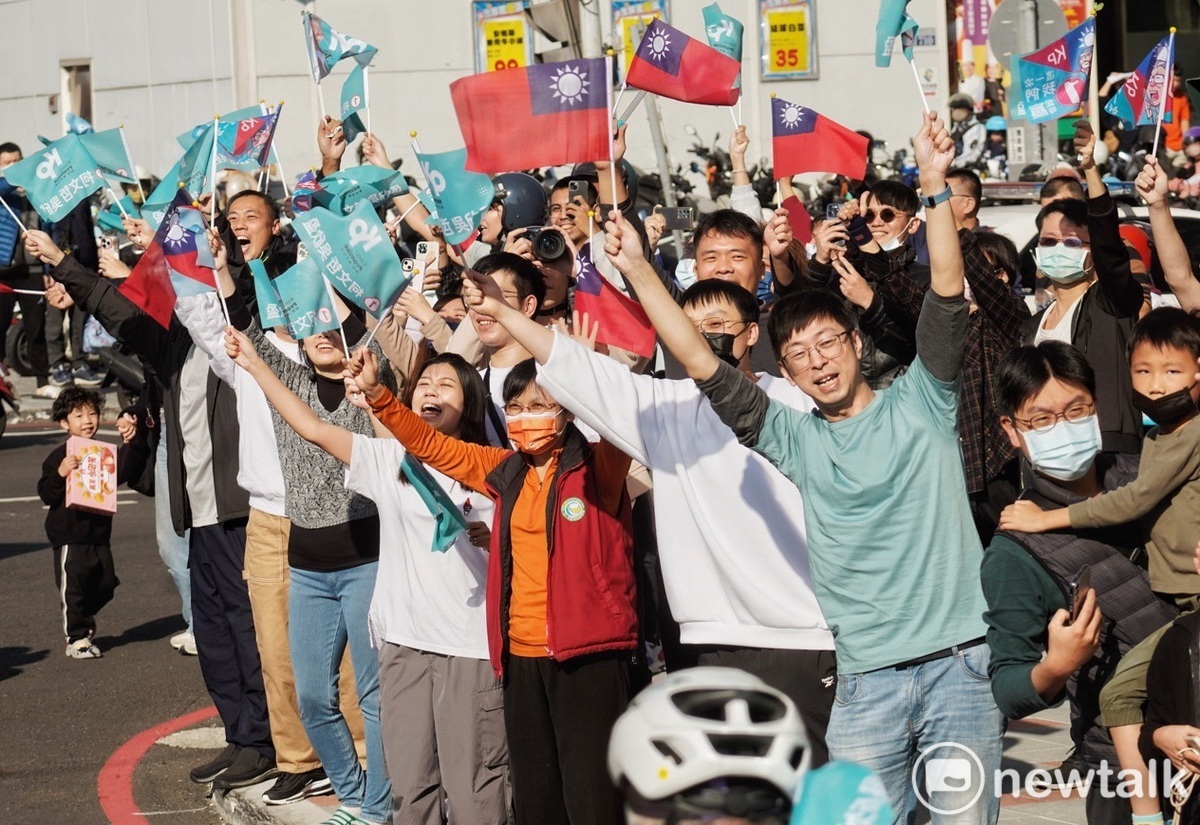 年輕的民眾黨支持者站在柯文哲掃街車隊行經的路旁，高舉旗幟為柯加油打氣。 圖：張良一/攝