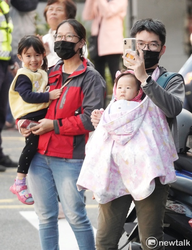 一對年輕夫婦抱著幼兒，在路旁等待柯的車隊到來。 圖：張良一/攝