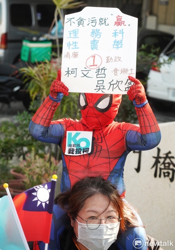 一位穿著蜘蛛人裝的小朋友舉著支持柯文哲的手舉牌，和家人一起站在路旁歡迎柯文哲。 圖：張良一/攝