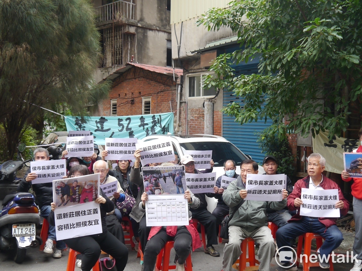 「新莊泰山合法房屋自救會」成員在侯友宜家族在新莊的土地前舉牌抗議，要求市府城鄉局將他們房屋重建的容積率比照侯友宜家辦理。 圖：林昀真/攝