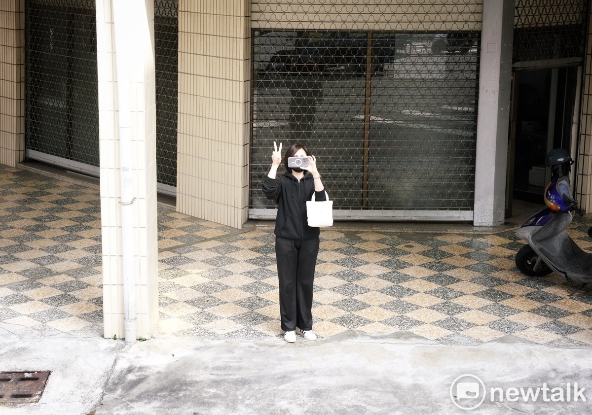 一位年輕的女性選民在賴清德掃街車隊經過時，邊拍照邊比出2號手勢。 圖：張良一/攝