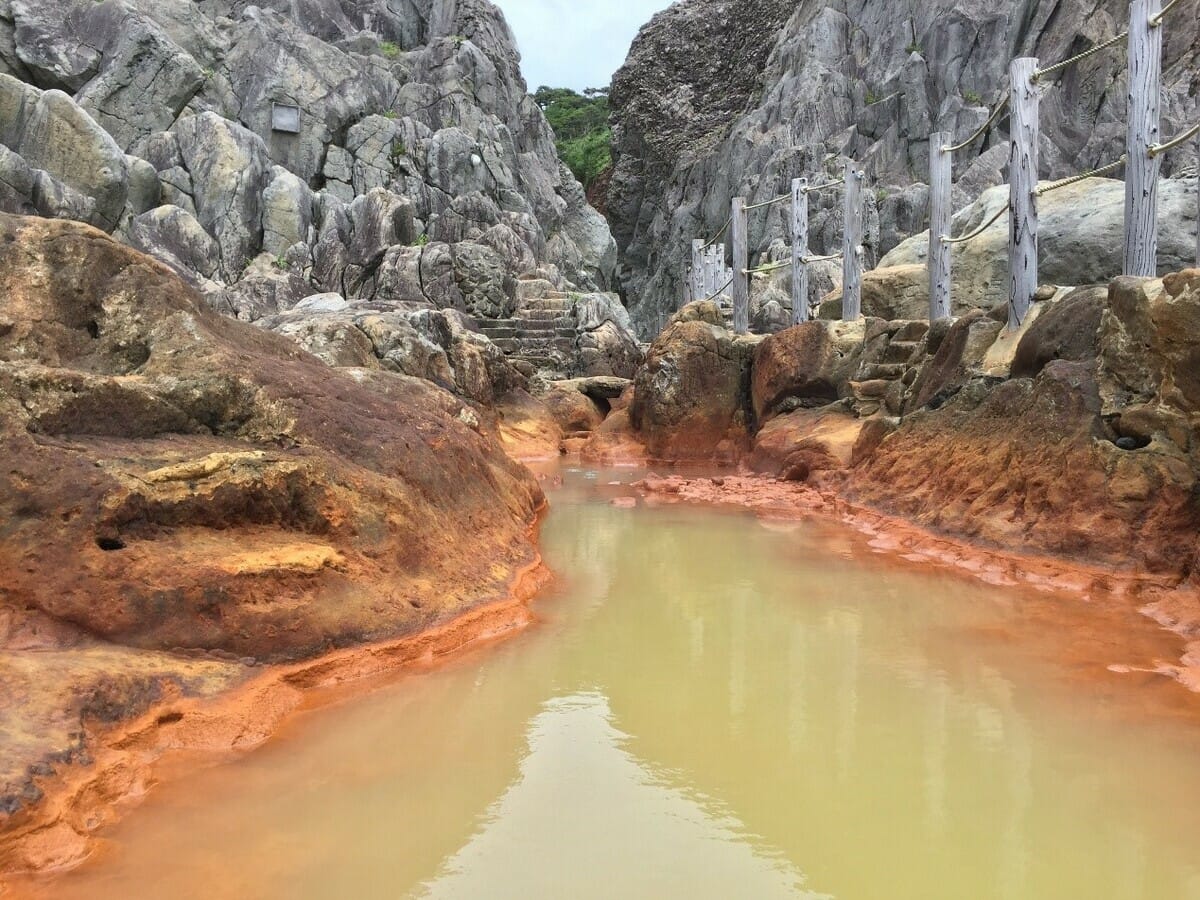 式根島「地鉈溫泉」是溫泉水流入海岸岩地所形成的潮池，退潮時溫度極高，要等到漲潮時混入海水才適合入浴。 圖：©TCVB／提供