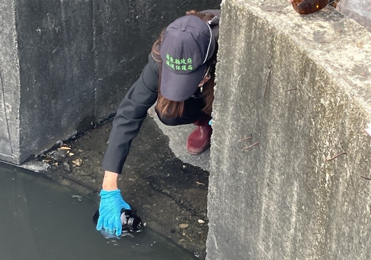 稽查人員採集萬丹大排溪水表層油花送驗。 圖：屏東縣政府/提供