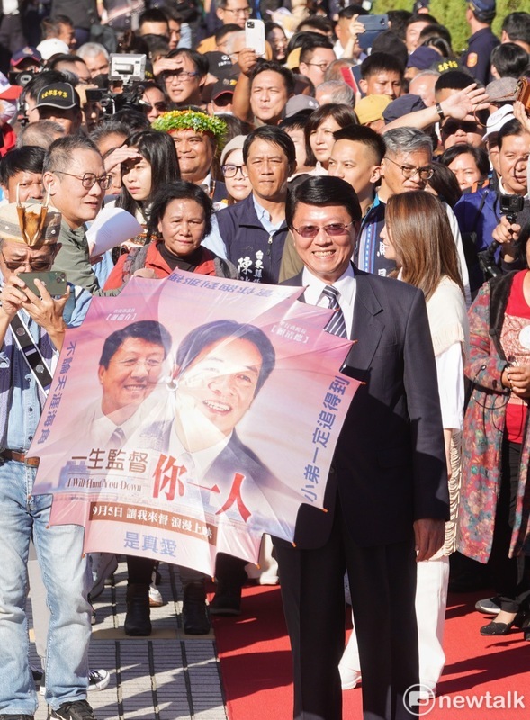 謝龍介手上拿著印有民進黨總統當選人賴清德與自己合照的粉紅色道具傘，還寫著「一生監督你一人」。 圖：張良一／攝