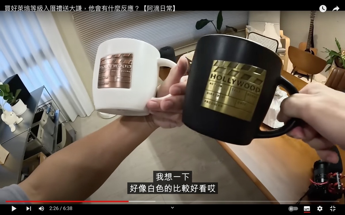 阿滴最後決定買上面印著金色場記板的馬克杯，並買了一黑一白，讓黃大謙選一個，另一個阿滴想要留著自己用。 圖：翻攝自阿滴日常YT頻道
