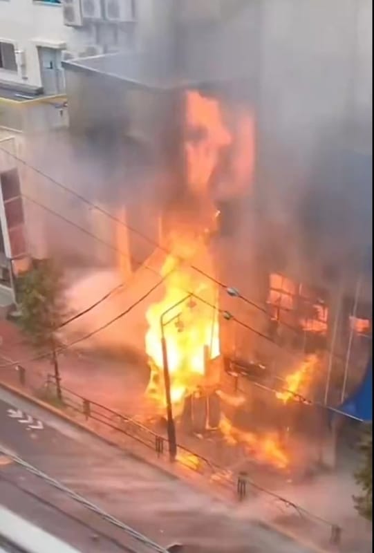 黃色招牌上印有「豚山」字樣的拉麵店遭到火焰吞沒，猛烈火勢更造成周邊地區瀰漫濃煙，自遠處就能明顯看到黑眼籠罩的模樣，相當驚人。 @FQpRgiLK7l5403